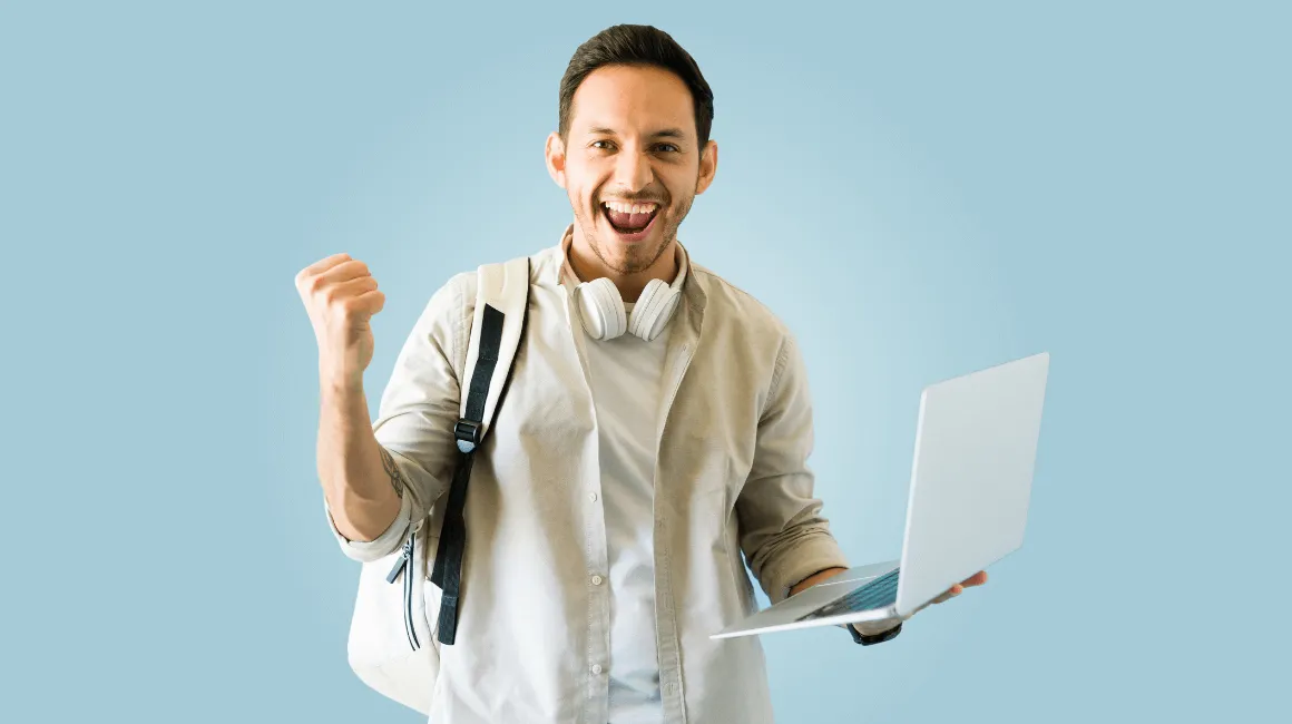 Młody mężczyzna z plecakiem i laptopem w dłoni cieszy się z sukcesu, unosi zaciśniętą pięść w geście radości; ma na szyi słuchawki, a w tle widać jednolite, jasnoniebieskie tło